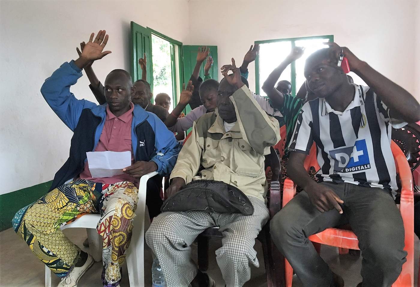 People raise their hands at a social cohesion meeting in District Three in Bangui. Photo: Tijs Magagi Hoornaert\/UN Migration Agency (IOM) 2017