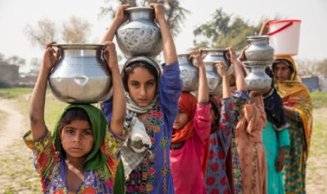 Women and girls wait in line at a water filtration plant set up by IOM Pakistan in Dadu District