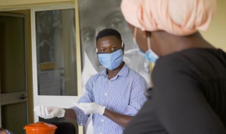Abdoulaye learns the correct method of wearing a mask and gloves from Dr. Fatoumata Sanassy Keita